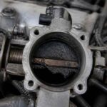 Zabrudzona przepustnica silnika z widoczną klapą i mechanizmem sterującym
