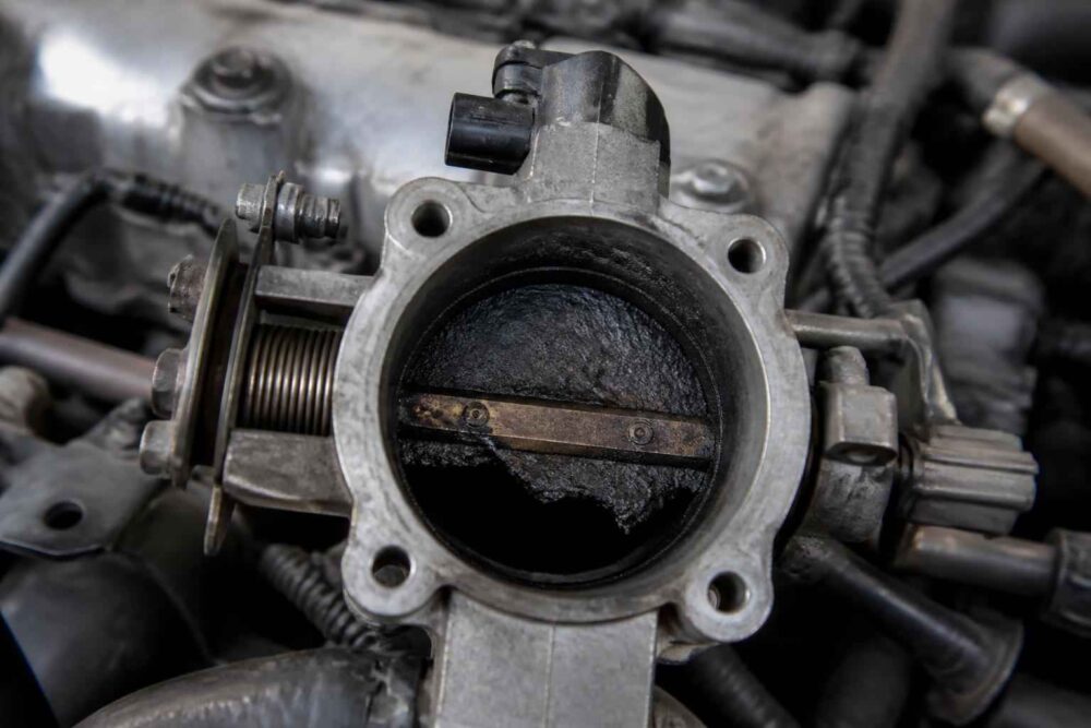 Zabrudzona przepustnica silnika z widoczną klapą i mechanizmem sterującym