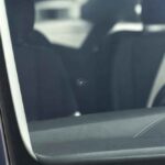 Fragment wnętrza samochodu z deską rozdzielczą i kierownicą widocznymi przez szybę kierowcy